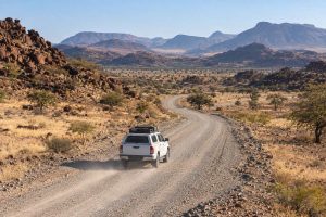 White 4x4 following a winding gravel road through Namibia’s rugged mountains on a self-drive trip.